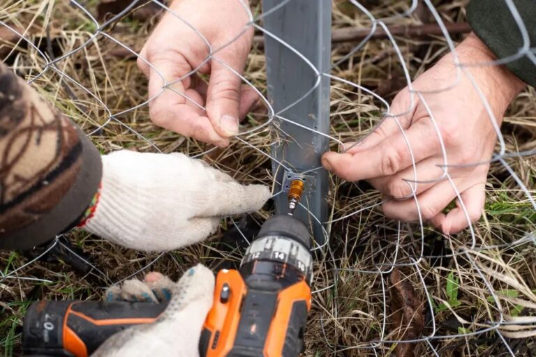 Dog Fence Wire Repair — two people securing chain link fencing to a post with a drill