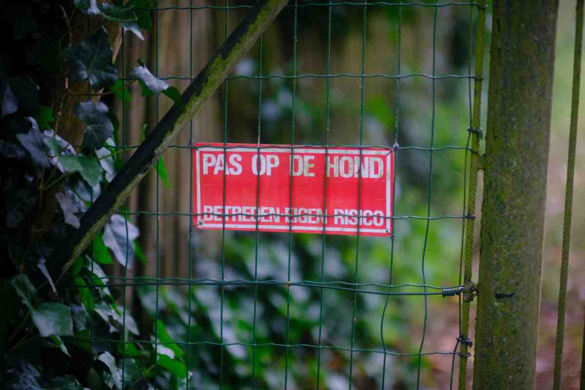 Red warning sign on wire fence highlighting invisible fence risks for dog owners
